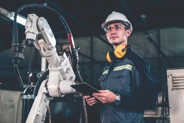 Trabajador joven de fábrica que trabaja con un brazo robótico experto — Foto de Stock