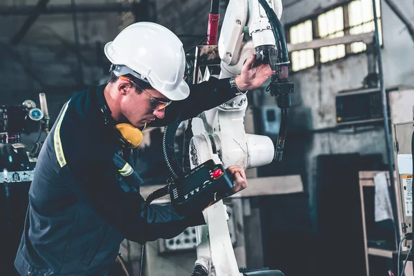 Genç fabrika işçisi usta bir robot kolla çalışıyor. — Stok fotoğraf