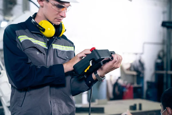 Jeune ouvrier d'usine travaillant avec un bras robotique compétent — Photo