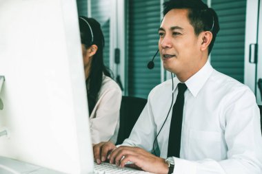 Kulaklık takan bir işadamı aktif olarak ofiste çalışıyor.