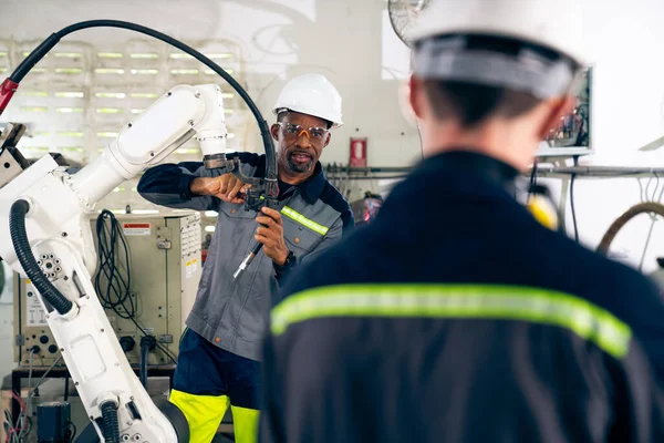 Travailleurs d'usine travaillant avec un bras robotique adepte dans un atelier — Photo