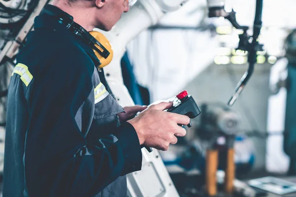 Genç fabrika işçisi usta bir robot kolla çalışıyor. — Stok fotoğraf