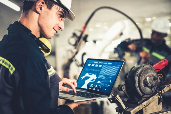 Genç fabrika işçisi usta bir robot kolla çalışıyor.