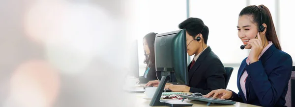 Vezetékes fülhallgatót viselő üzletemberek széles látókörben dolgoznak az irodában — Stock Fotó