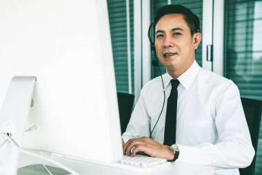 Kulaklık takan bir işadamı aktif olarak ofiste çalışıyor.