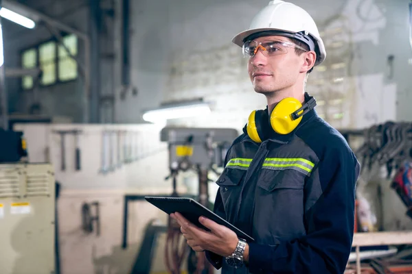 Trabajador joven de la fábrica usando tableta adepta en un edificio del taller — Foto de Stock