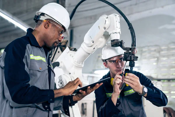Працівники заводу працюють з майстерною роботизованою рукою в майстерні — стокове фото