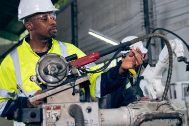 Uzman robotik kolla çalışan Afrikalı Amerikalı fabrika işçisi