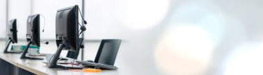 Call center computers and headsets all in office in widen view