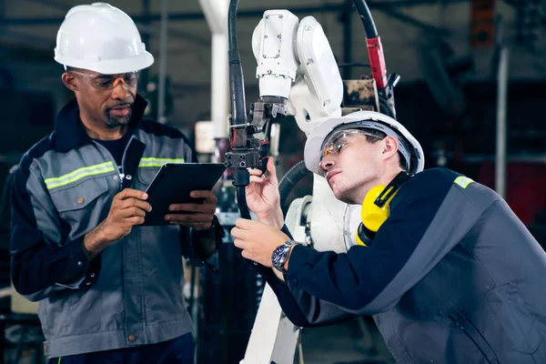 Pracownicy fabryki pracujący z robotycznym ramieniem wwarsztacie — Zdjęcie stockowe