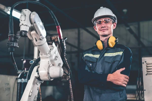 Jovem trabalhador da fábrica que trabalha com braço robótico adepto — Fotografia de Stock