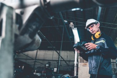 Genç fabrika işçisi usta bir robot kolla çalışıyor.