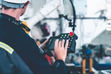 Genç fabrika işçisi usta bir robot kolla çalışıyor.