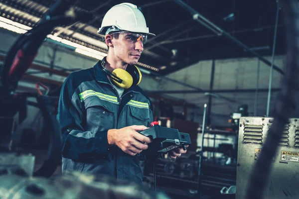 Genç fabrika işçisi usta bir robot kolla çalışıyor. — Stok fotoğraf