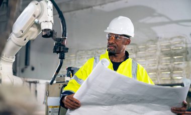 Uzman robotik kolla çalışan Afrikalı Amerikalı fabrika işçisi