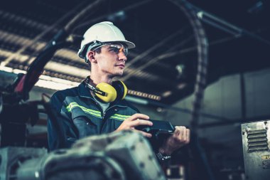 Genç fabrika işçisi usta bir robot kolla çalışıyor.