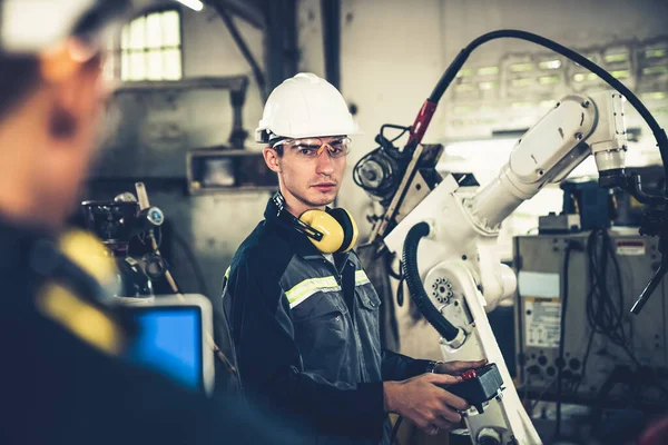 Pracownicy fabryki pracujący z robotycznym ramieniem wwarsztacie — Zdjęcie stockowe