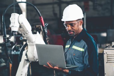 Uzman robotik kolla çalışan Afrikalı Amerikalı fabrika işçisi