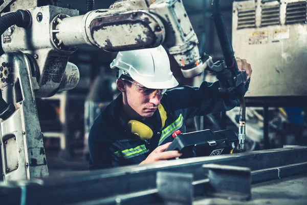 Genç fabrika işçisi usta bir robot kolla çalışıyor. — Stok fotoğraf