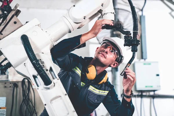 Genç fabrika işçisi usta bir robot kolla çalışıyor.