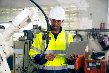 Uzman robotik kolla çalışan Afrikalı Amerikalı fabrika işçisi