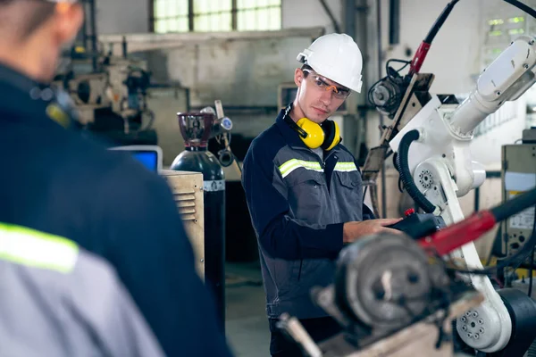Працівники заводу працюють з майстерною роботизованою рукою в майстерні — стокове фото