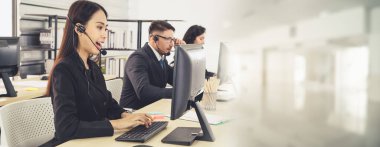 Ofiste çalışan kulaklık takan işadamları uzak müşteri ya da meslektaşlarını desteklemek için çalışıyorlar. Çağrı merkezi, tele pazarlama, müşteri destek acentesi geniş görünümde hizmet sunar .