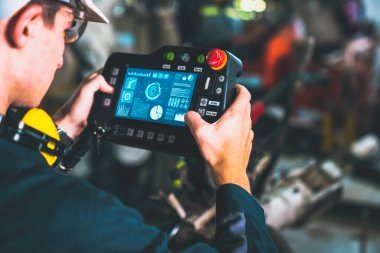 Genç fabrika işçisi usta bir robot kolla çalışıyor.