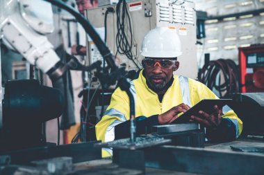 Uzman robotik kolla çalışan Afrikalı Amerikalı fabrika işçisi