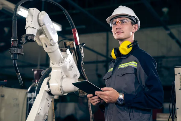 Giovane operaio di fabbrica che lavora con braccio robotico abile — Foto Stock