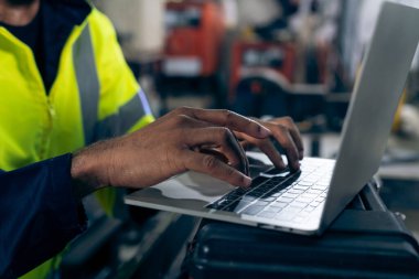 İşçi, dizüstü bilgisayarla çalışarak düzgün işlem listesi hazırlıyor.