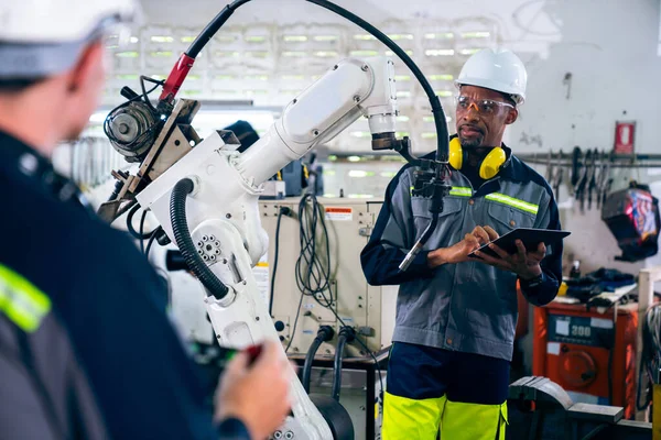 Travailleurs d'usine travaillant avec un bras robotique adepte dans un atelier — Photo