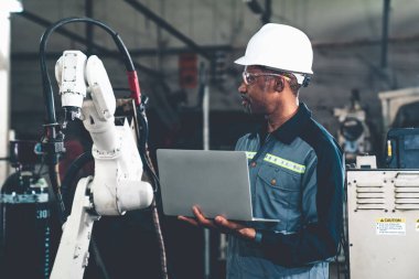 Uzman robotik kolla çalışan Afrikalı Amerikalı fabrika işçisi