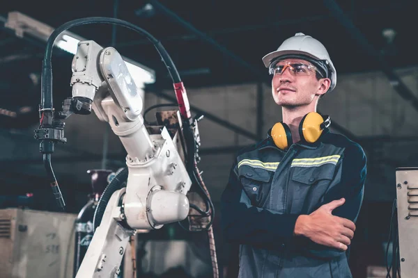 Giovane operaio di fabbrica che lavora con braccio robotico abile — Foto Stock
