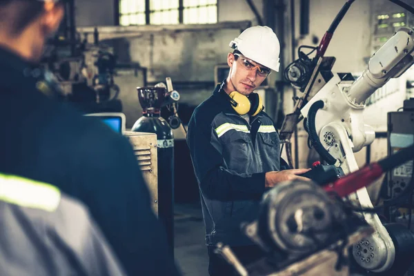Trabajadores de la fábrica que trabajan con un brazo robótico experto en un taller —  Fotos de Stock