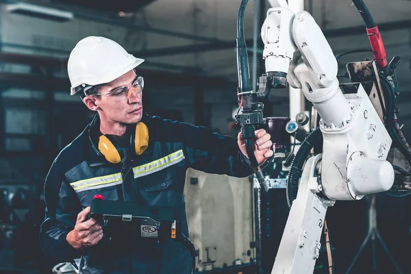 Молодий заводський працівник, що працює з майстерною роботизованою рукою — стокове фото