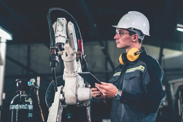 Trabajador joven de fábrica que trabaja con un brazo robótico experto —  Fotos de Stock