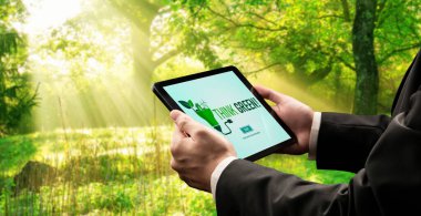 Çevre tasarrufu ve ESG iş konsepti için yeşil iş dönüşümü. İşadamı, çevre dostu yönetime ve alternatif temiz enerji kullanımına yönelik kurumsal bir hedef belirlemek için tablet kullanıyor.