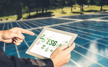 Çevre tasarrufu ve ESG iş konsepti için yeşil iş dönüşümü. İşadamı, çevre dostu yönetime ve alternatif temiz enerji kullanımına yönelik kurumsal bir hedef belirlemek için tablet kullanıyor.
