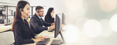 Ofiste çalışan kulaklık takan işadamları uzak müşteri ya da meslektaşlarını desteklemek için çalışıyorlar. Çağrı merkezi, tele pazarlama, müşteri destek acentesi geniş görünümde hizmet sunar .