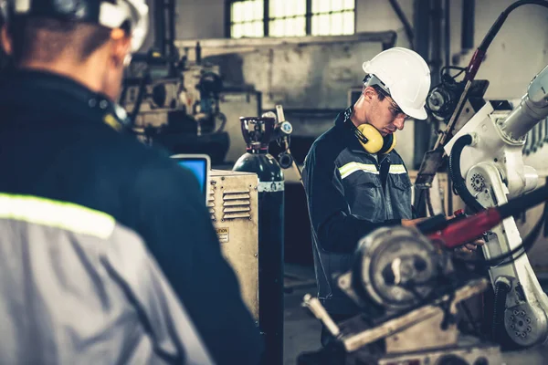 Fabrika işçileri bir atölyede uzman robot kolla çalışıyorlar. Otomatik üretim teknolojisi için endüstriyel robot programlama yazılımı .