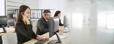 Ofiste çalışan kulaklık takan işadamları uzak müşteri ya da meslektaşlarını desteklemek için çalışıyorlar. Çağrı merkezi, tele pazarlama, müşteri destek acentesi geniş görünümde hizmet sunar .