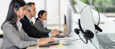 Ofiste çalışan kulaklık takan işadamları uzak müşteri ya da meslektaşlarını desteklemek için çalışıyorlar. Çağrı merkezi, tele pazarlama, müşteri destek acentesi geniş görünümde hizmet sunar .