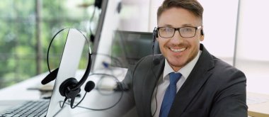 Ofiste çalışan kulaklık takan işadamları uzak müşteri ya da meslektaşlarını desteklemek için çalışıyorlar. Çağrı merkezi, tele pazarlama, müşteri destek acentesi geniş görünümde hizmet sunar .