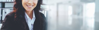 Geniş görünüm panorama panorama pankartındaki çağrı merkezi ya da müşteri destek ajansı, telefon konferansında uzak müşteri ya da iş arkadaşını desteklemek için ofiste çalışırken kulaklık takıyor.