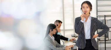 Ofiste çalışan kulaklık takan işadamları uzak müşteri ya da meslektaşlarını desteklemek için çalışıyorlar. Çağrı merkezi, tele pazarlama, müşteri destek acentesi geniş görünümde hizmet sunar .