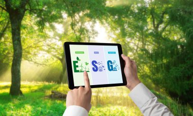 Çevre tasarrufu ve ESG iş konsepti için yeşil iş dönüşümü. İşadamı, çevre dostu yönetime ve alternatif temiz enerji kullanımına yönelik kurumsal bir hedef belirlemek için tablet kullanıyor.