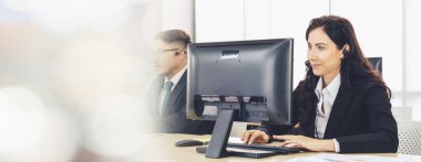 Ofiste çalışan kulaklık takan işadamları uzak müşteri ya da meslektaşlarını desteklemek için çalışıyorlar. Çağrı merkezi, tele pazarlama, müşteri destek acentesi geniş görünümde hizmet sunar .