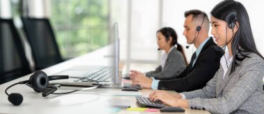 Ofiste çalışan kulaklık takan işadamları uzak müşteri ya da meslektaşlarını desteklemek için çalışıyorlar. Çağrı merkezi, tele pazarlama, müşteri destek acentesi geniş görünümde hizmet sunar .