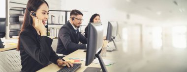 Ofiste çalışan kulaklık takan işadamları uzak müşteri ya da meslektaşlarını desteklemek için çalışıyorlar. Çağrı merkezi, tele pazarlama, müşteri destek acentesi geniş görünümde hizmet sunar .